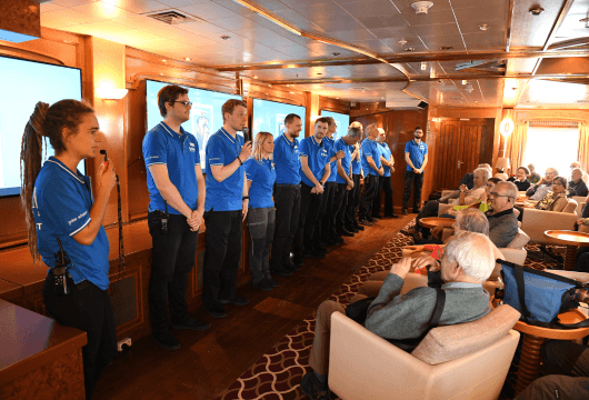 Das gesamte Expeditionsteam stellt sich den Gästen in der Lounge des Schiffs vor.